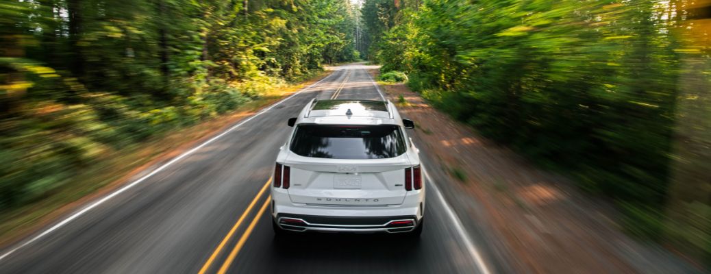 The 2022 Kia Sorento driving in a road by the trees