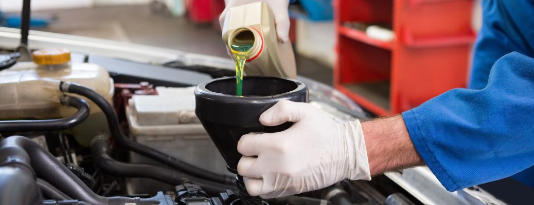 Where in San Leandro, CA, Can I Get an Oil Change for My Kia? Man pouring oil into the engine of a vehicle.