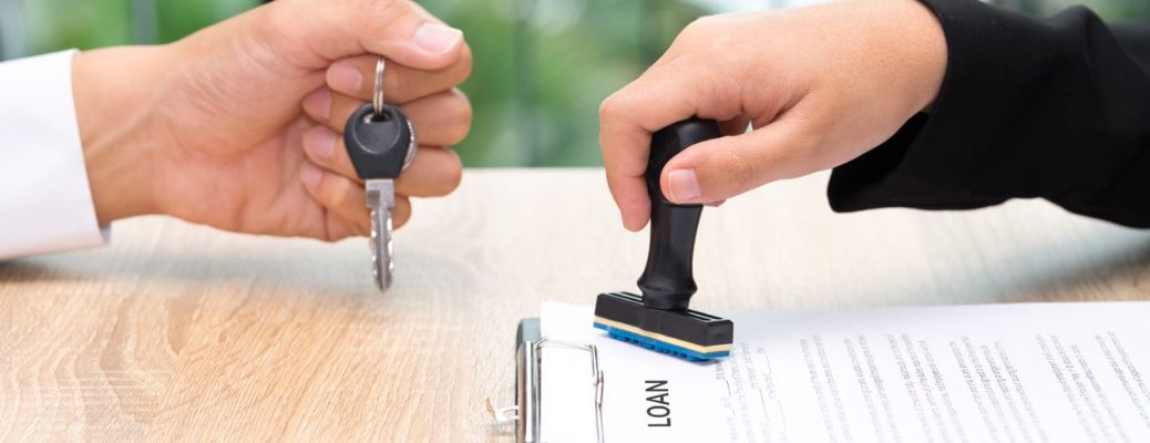 one hand stamping a car loan application and another hand giving the keys